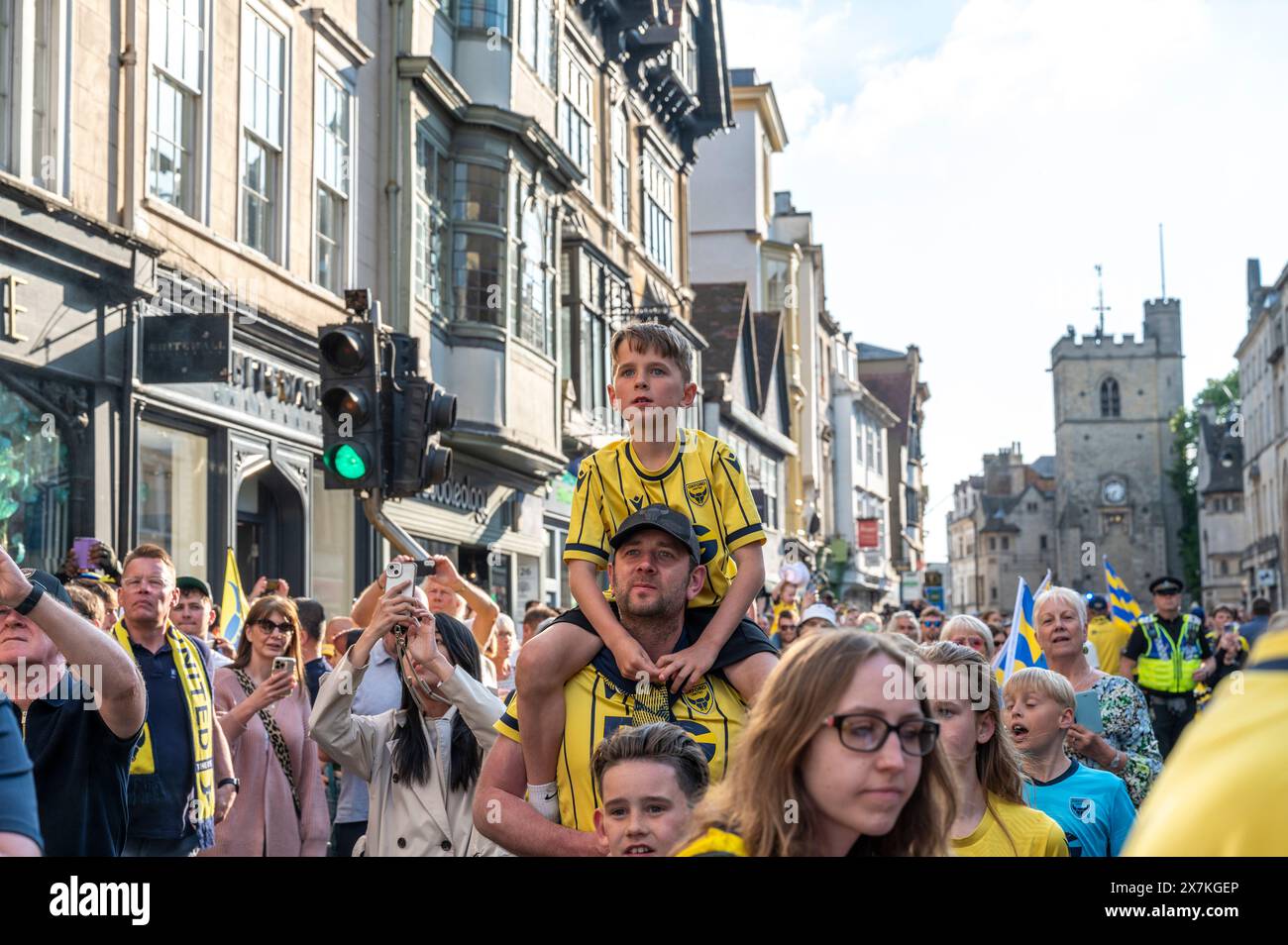 Thousands of Oxford United fans lined the city centre of Oxford to celebrate the promotion of Oxford United to the EFL Championship after beating the Bolton Wanders in the League One playoff at Wembley on the weekend. The crowds, decked out in yellow, cheered loudly and let off yellow flares as the open-top bus carrying the team and staff slowly moved along the High Street to the Oxford City Town Hall, where they attended an invite-only civic reception. The Oxford United flag flew over the Oxford City Council building in celebration. Stock Photo