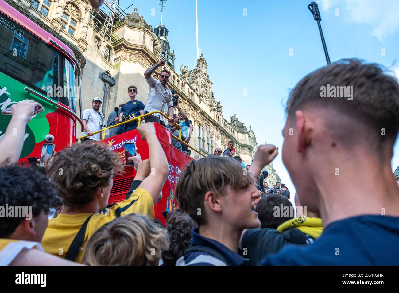 Thousands of Oxford United fans lined the city centre of Oxford to celebrate the promotion of Oxford United to the EFL Championship after beating the Bolton Wanders in the League One playoff at Wembley on the weekend. The crowds, decked out in yellow, cheered loudly and let off yellow flares as the open-top bus carrying the team and staff slowly moved along the High Street to the Oxford City Town Hall, where they attended an invite-only civic reception. The Oxford United flag flew over the Oxford City Council building in celebration. Stock Photo