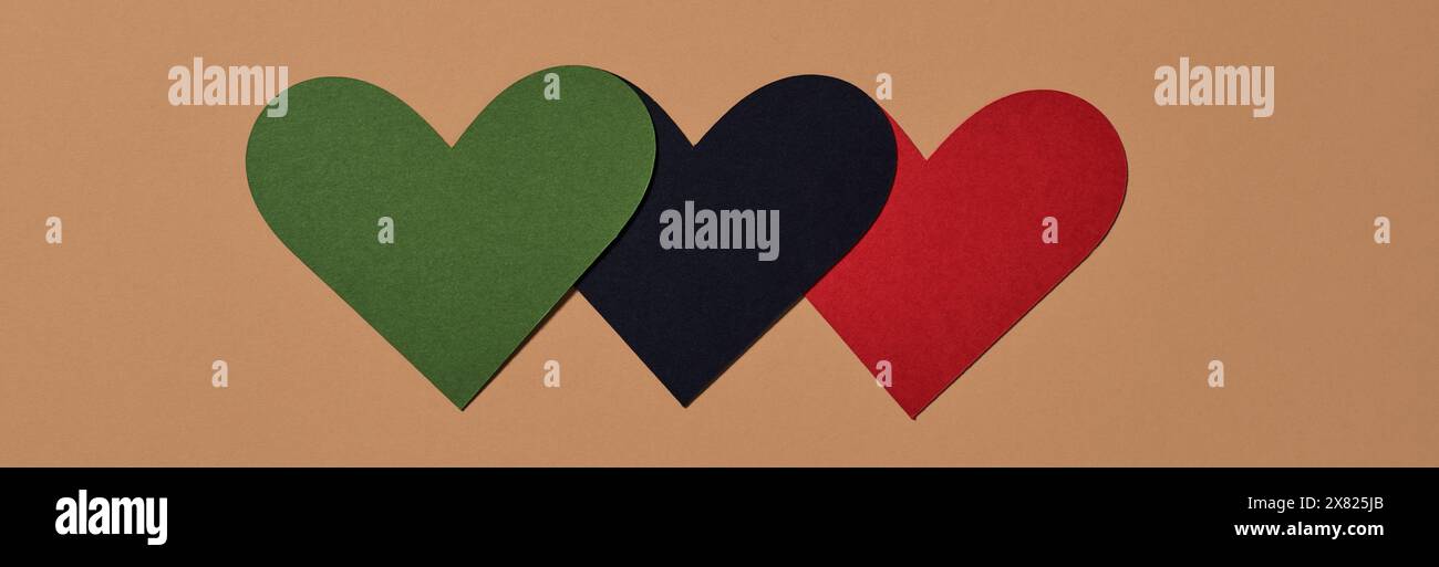 three hearts with the colors of the black liberation flag, green, black and red, on a brown background, in a panoramic format to use as web banner Stock Photo