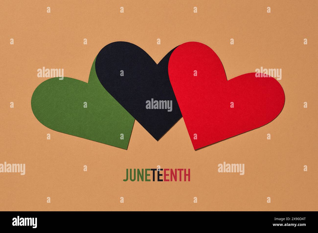 three hearts with the colors of the black liberation flag, green, black and red, and the the text juneteenth on a brown background Stock Photo