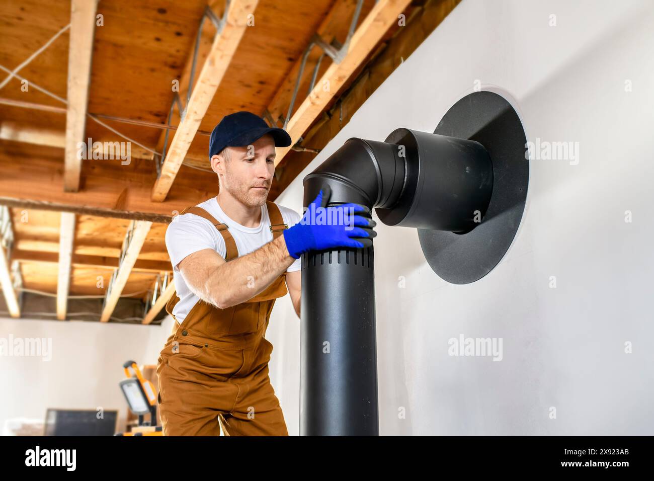 male worker preparing a chimney installation for a modern, energy saving heating stove. Stock Photo