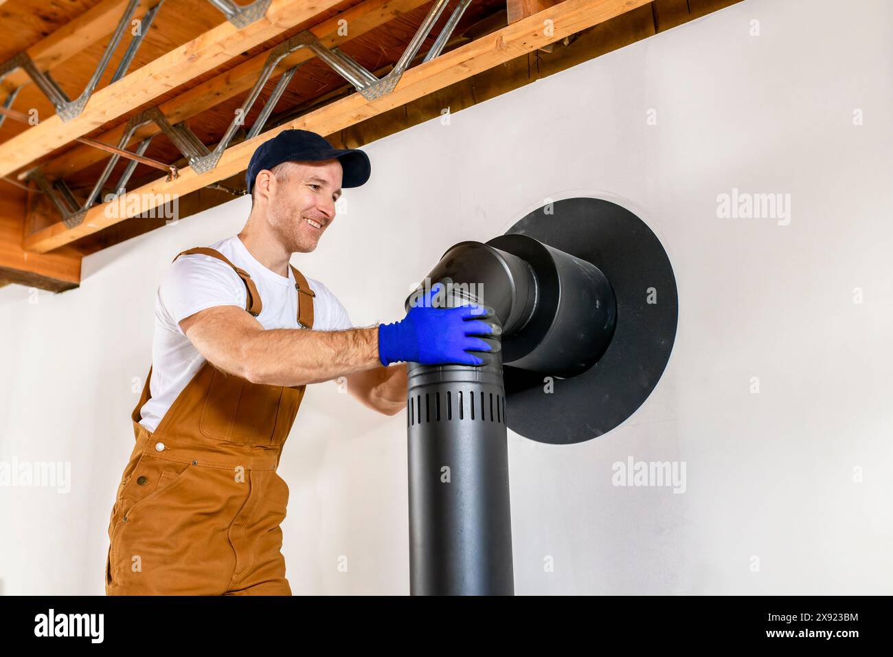 male worker preparing a chimney installation for a modern, energy saving heating stove. Stock Photo