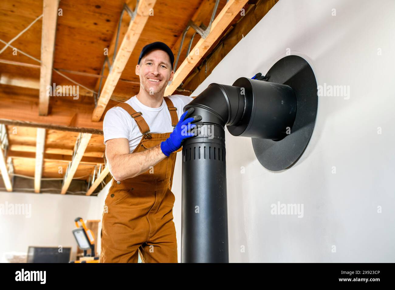 male worker preparing a chimney installation for a modern, energy saving heating stove. Stock Photo