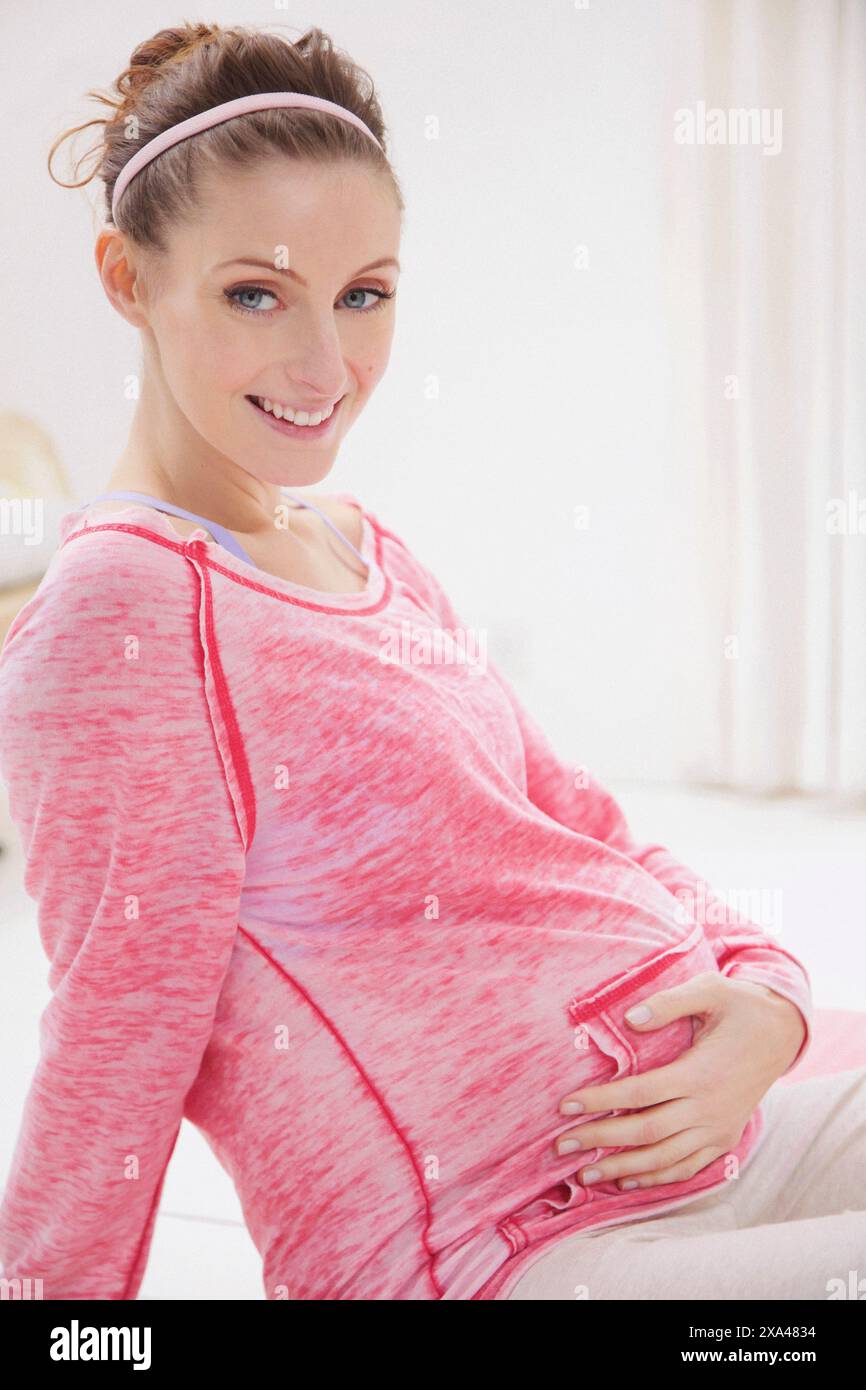 Smiling Pregnant Woman Holding her Stomach Stock Photo - Alamy