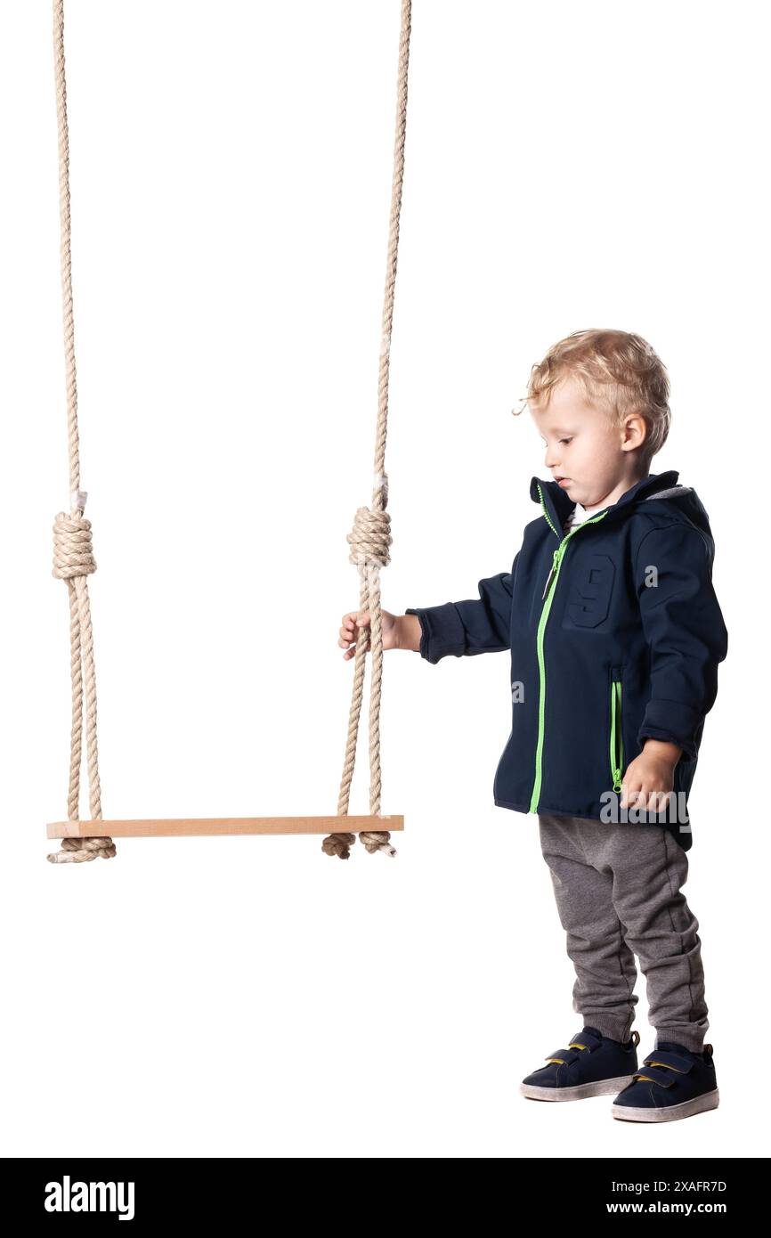 Young boy dressed in casual attire holding a swing, isolated on white background. Perfect image for childhood, playtime, and carefree moments. Stock Photo