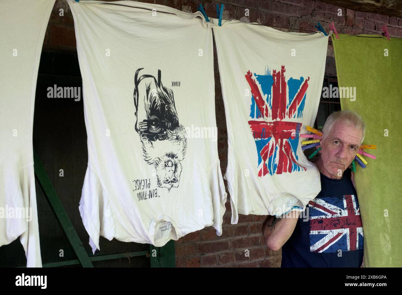 mature male with clothes pegs on ears entertaining children while pegging laundry out to dry on clothes line zala county hungary Stock Photo