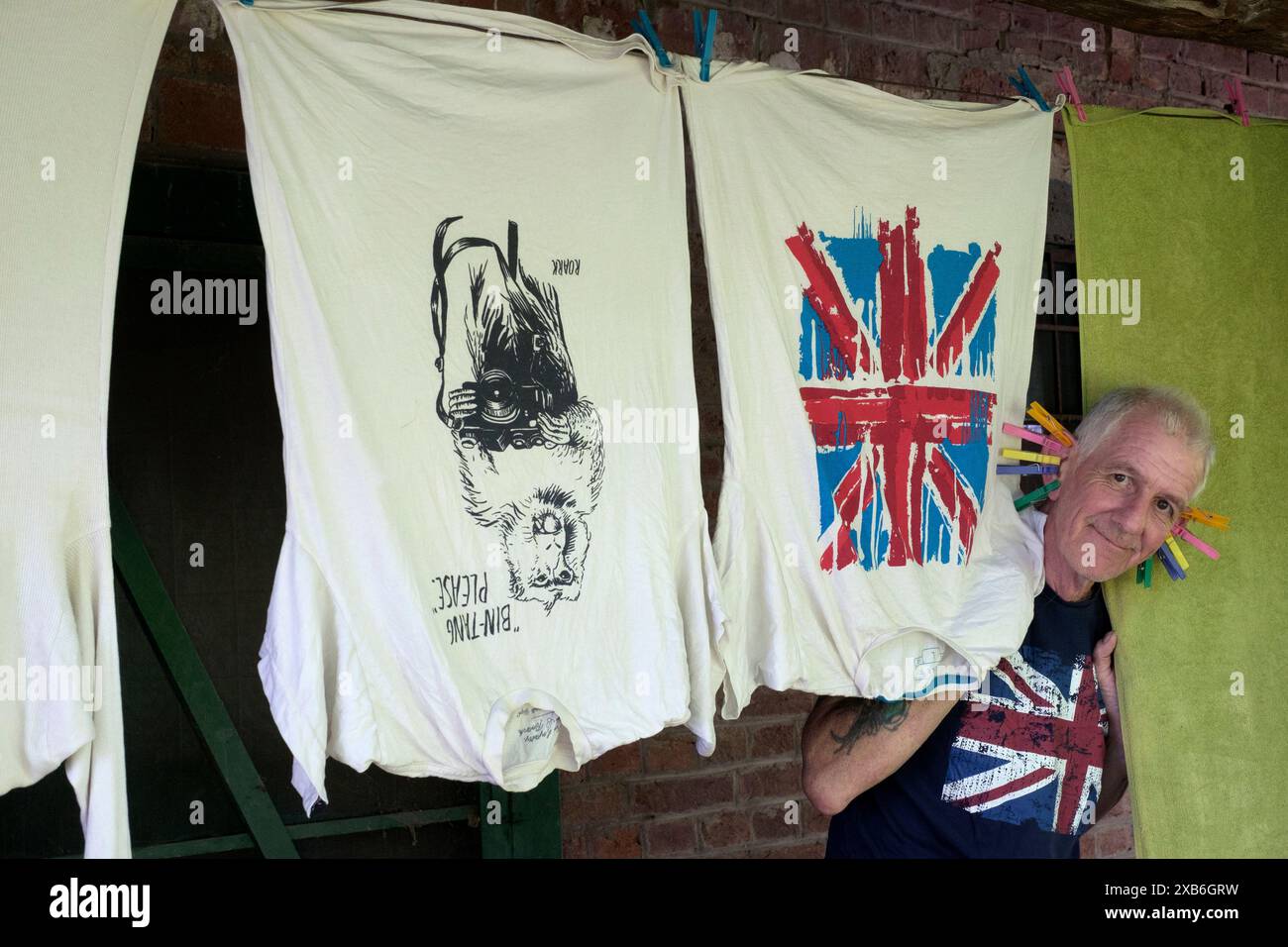 mature male with clothes pegs on ears entertaining children while pegging laundry out to dry on clothes line zala county hungary Stock Photo