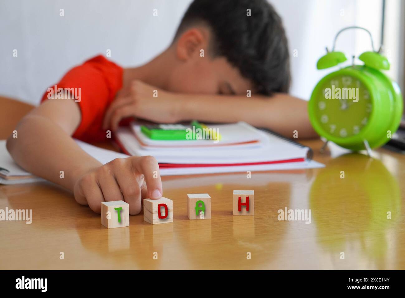 child surrounded by books and notebooks frustrated, with the acronym ADHD, represents the disease Attention Deficit Disorder and the difficulties it e Stock Photo