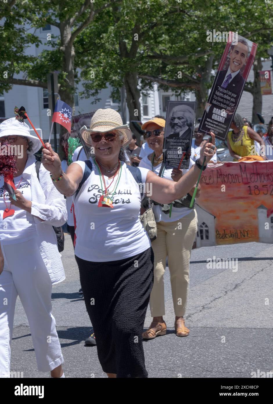 A member of the Peekskill Seniors Club marches in the Junteenth Parade holding a flag and a photo of President Obama. In Peekskill, June 2024. Stock Photo