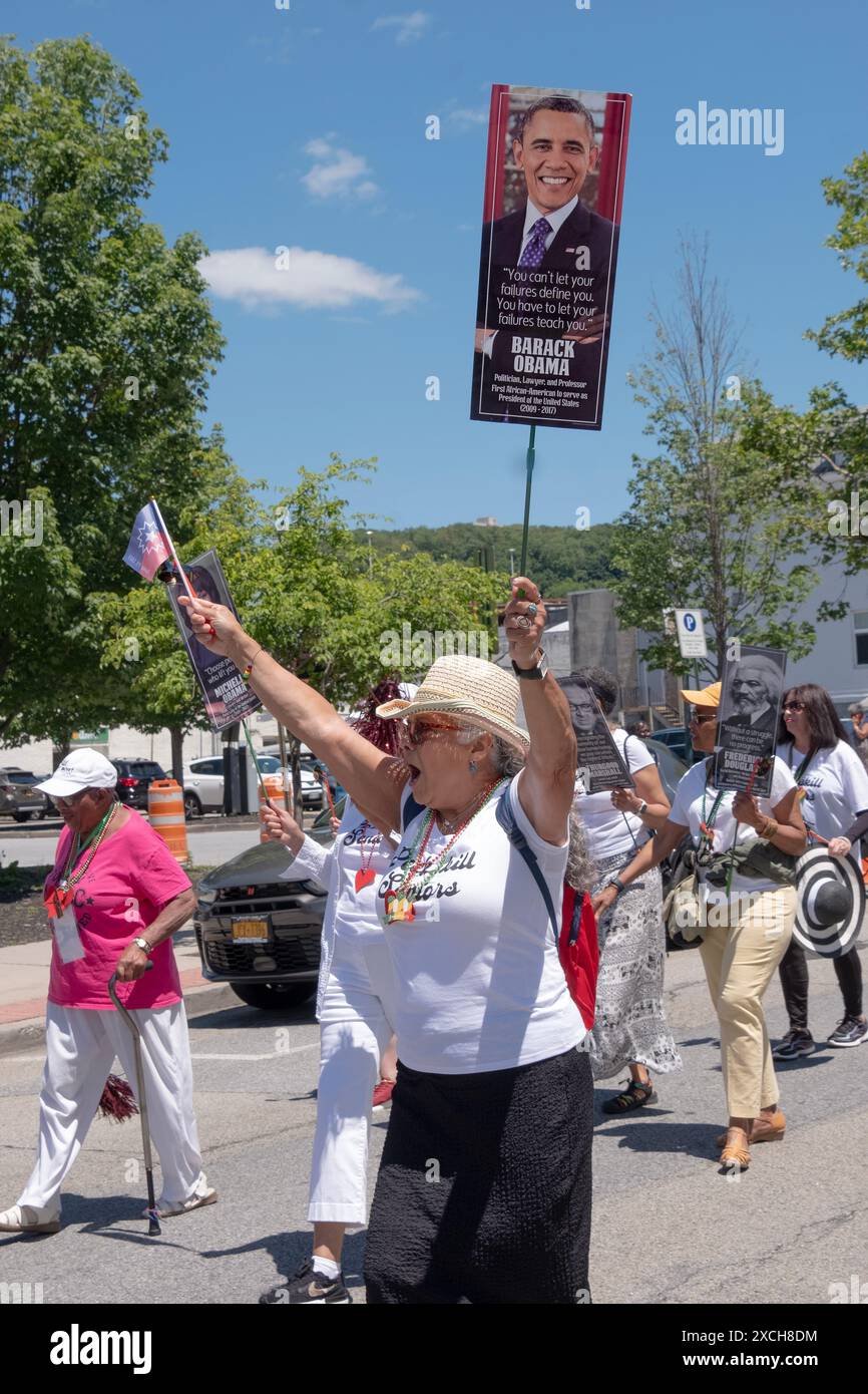 A member of the Peekskill Seniors Club marches in the Junteenth Parade holding a flag and a photo of President Obama. In Peekskill, June 2024. Stock Photo