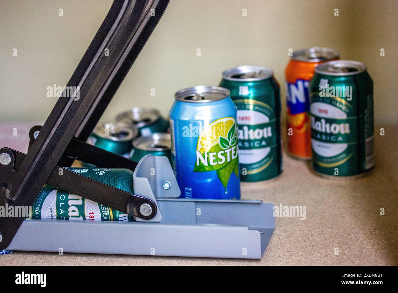 Madrid, Spain. May 1, 2024 Crusher, press, shredder for aluminum cans from water, sourdough, beer. Mahou beer, Nestie drink, Fanta. Plastic recycling. Stock Photo