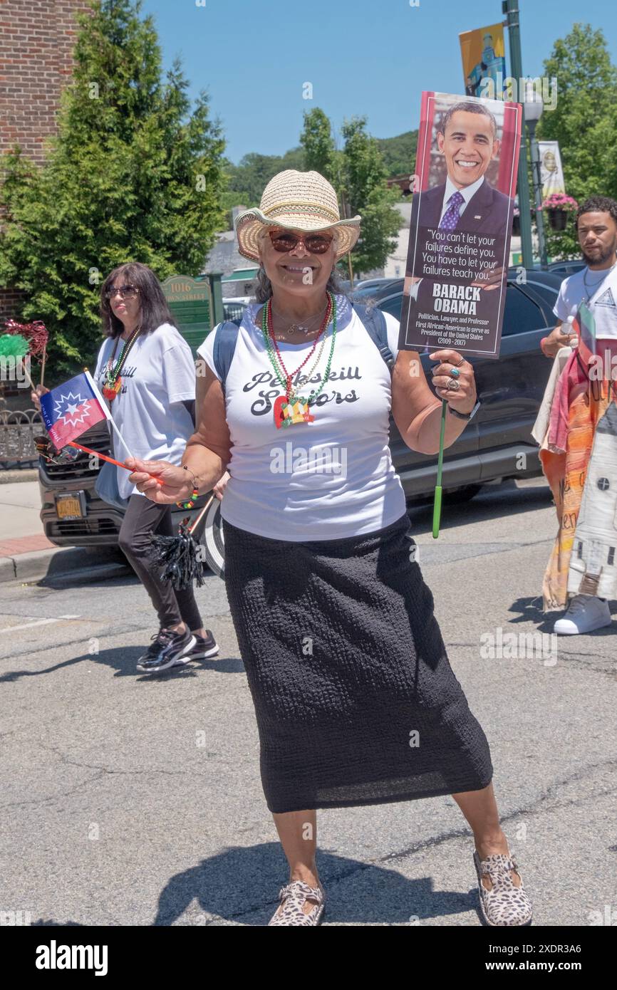 A member of the Peekskill Seniors Club marches in the Junteenth Parade holding a flag and a photo of President Obama. In Peekskill, June 2024. Stock Photo