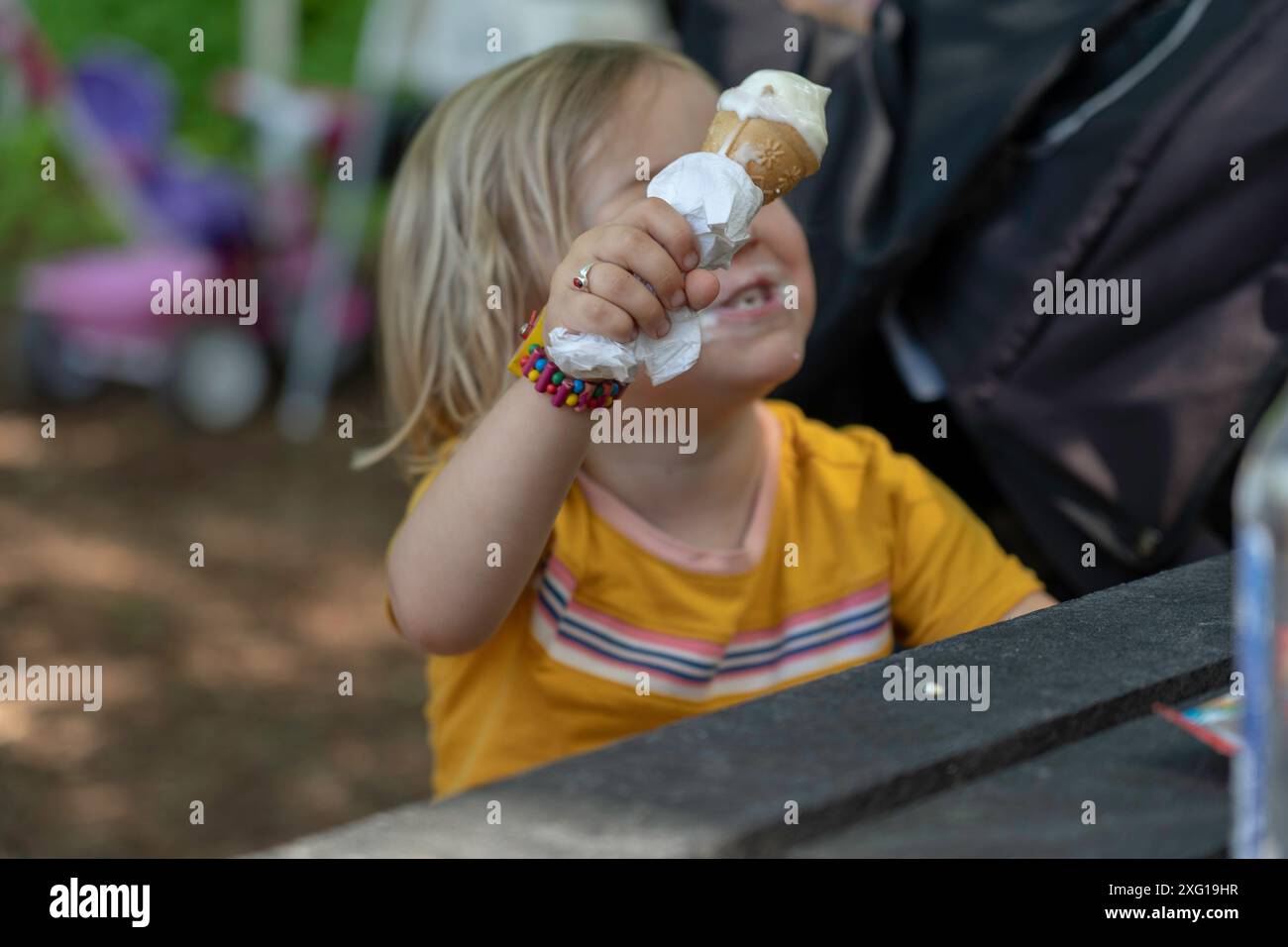 Caucasian girl child eating ice cream on a cone in summer Stock Photo