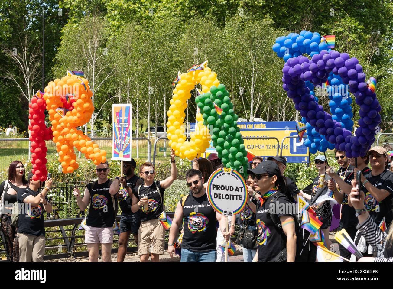 Deloitte staff with rainbow coloured balloon letters spelling out 'Proud' and a message 'Proud at Deloitte' at the London pride parade, 29th June 2024 Stock Photo