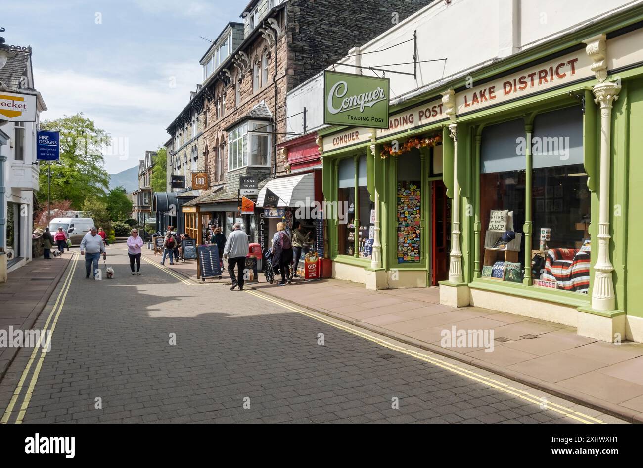 People tourists visitors walking in the street town centre in spring Lake Road Keswick Cumbria England UK United Kingdom GB Great Britain Stock Photo