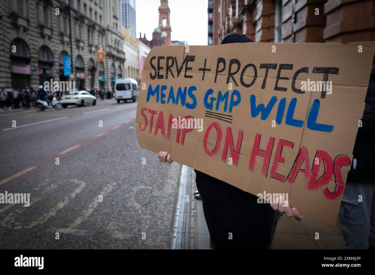 Manchester, UK. 25th July, 2024. A protester with a placard stands outside Andy Burnhams office to protest against the GMP. A man was violently assaulted by a police officer while being arrested at Manchester airport. The incident took place on Tuesday when police intervened in an altercation between members of the public in terminal 2 of the airport. Credit: Andy Barton/Alamy Live News Stock Photo