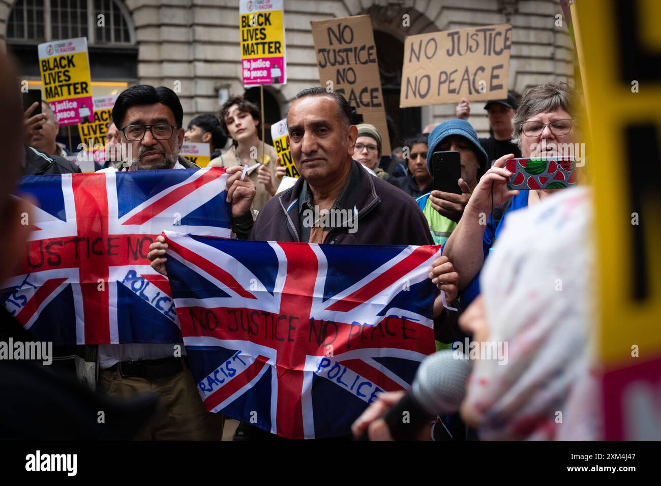 Manchester, UK. 25th July, 2024. Protesters with placards gather outside Andy Burnhams office to protest against the GMP. A man was violently assaulted by a police officer while being arrested at Manchester airport. The incident took place on Tuesday when police intervened in an altercation between members of the public in terminal 2 of the airport. Credit: Andy Barton/Alamy Live News Stock Photo