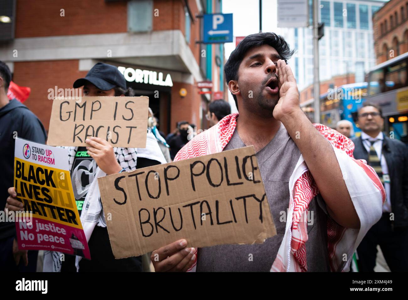 Manchester, UK. 25th July, 2024. Protesters with placards gather outside Andy Burnhams office to protest against the GMP. A man was violently assaulted by a police officer while being arrested at Manchester airport. The incident took place on Tuesday when police intervened in an altercation between members of the public in terminal 2 of the airport. Credit: Andy Barton/Alamy Live News Stock Photo