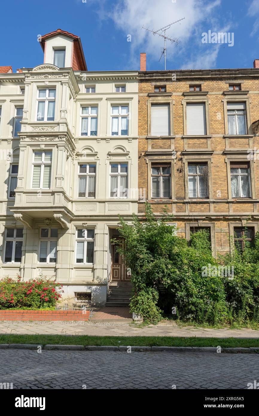 A renovated and a dilapidated terraced house with several floors and a front garden Stock Photo