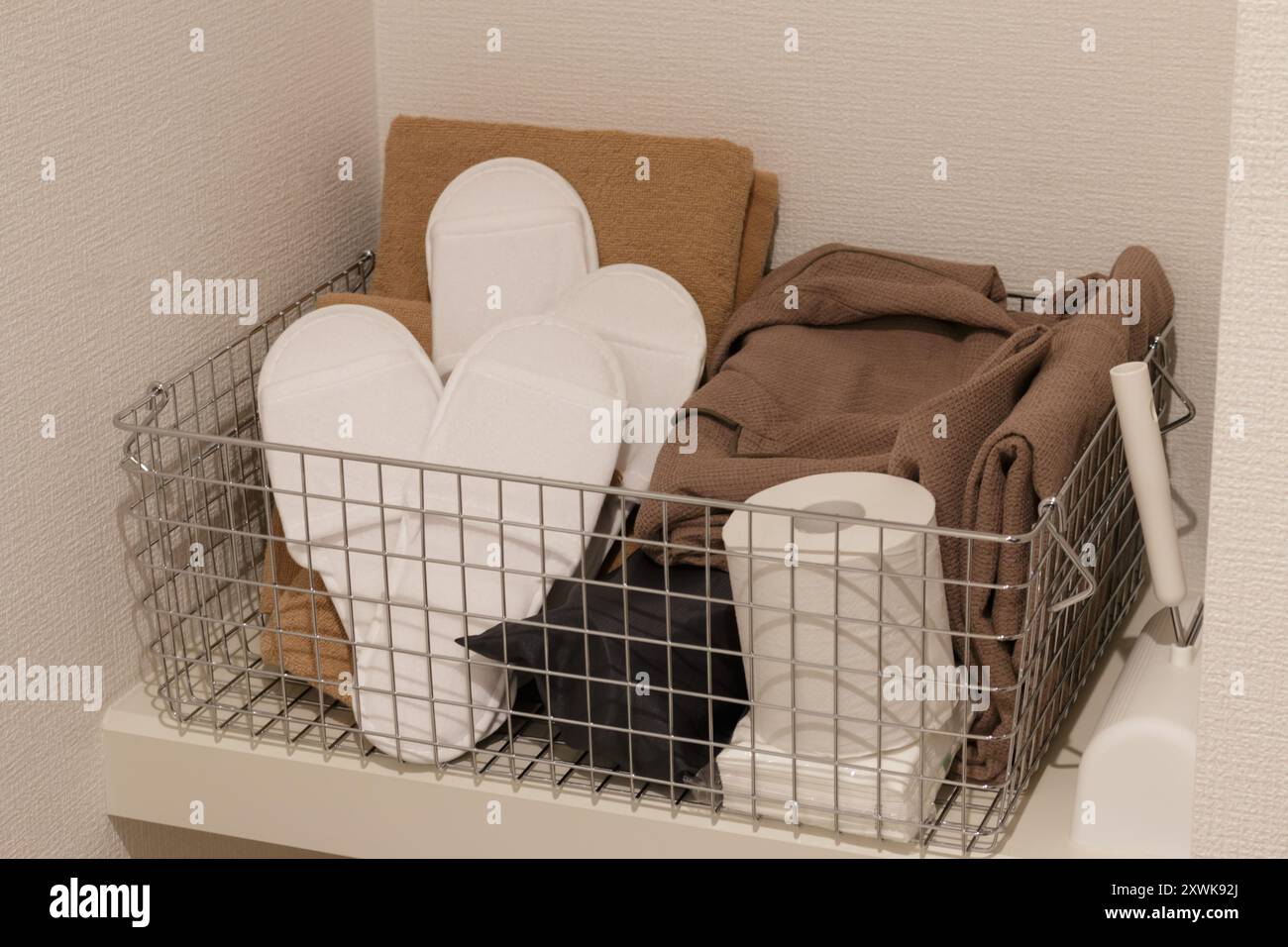 Hotel slippers brown towels and toilet paper in basket Stock Photo