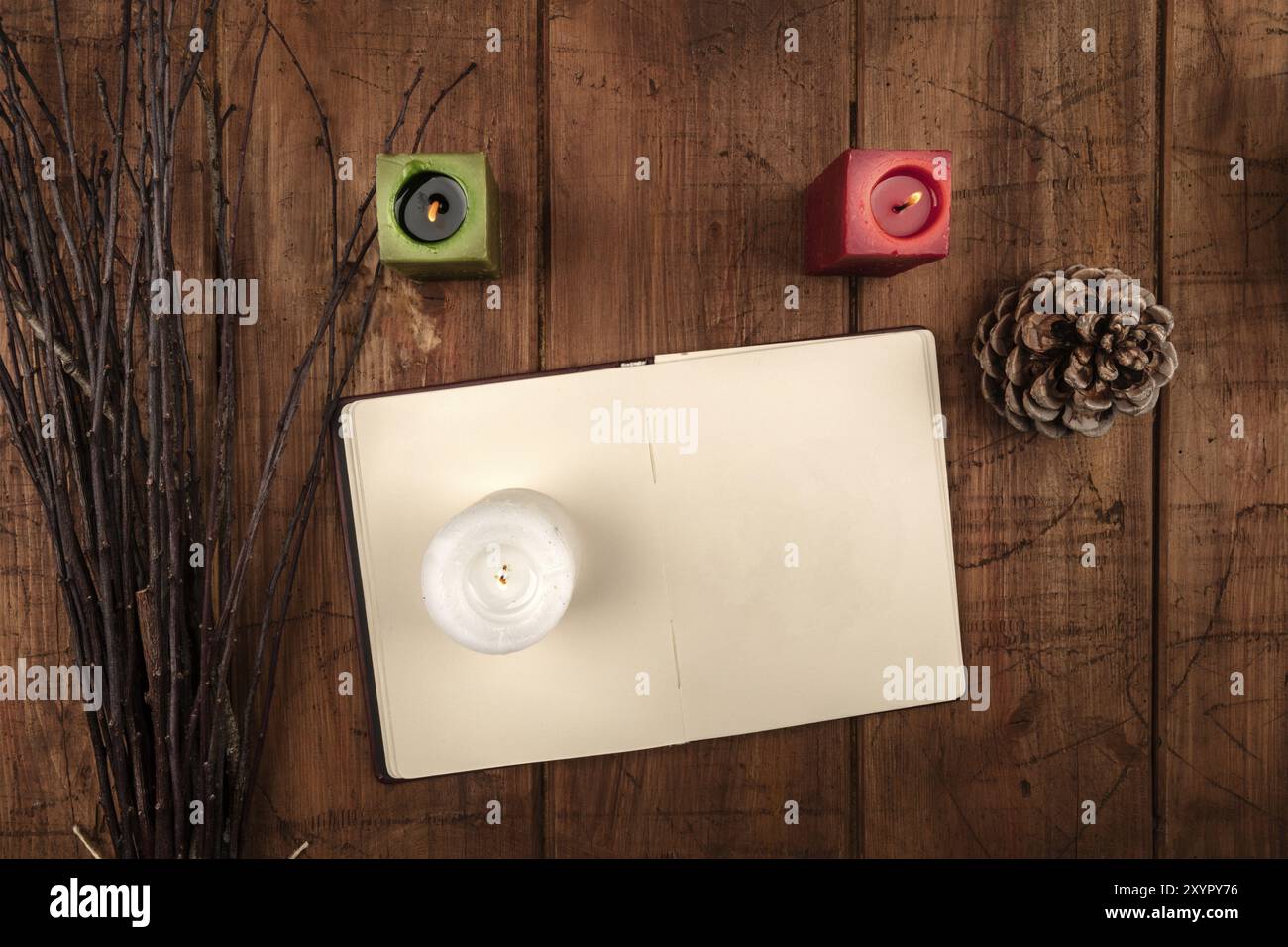 An overhead photo of an open grimoire, candles, a pine cone, and a handmade broom. Wiccan ritual objects, shot from above on a dark background with a Stock Photo