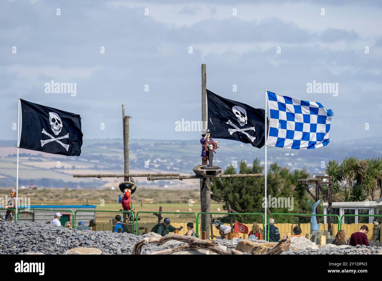 Jolly Roger skull and crossbones flags and blue chequered flag flying over crazy golf course at Westward Ho, Devon, UK on 3 September 2024 Stock Photo