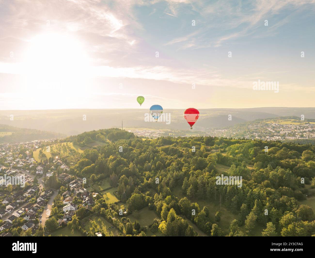 View of several hot air balloons over a wooded landscape at sunset near a town, Calw, Black Forest, Germany, Europe Stock Photo