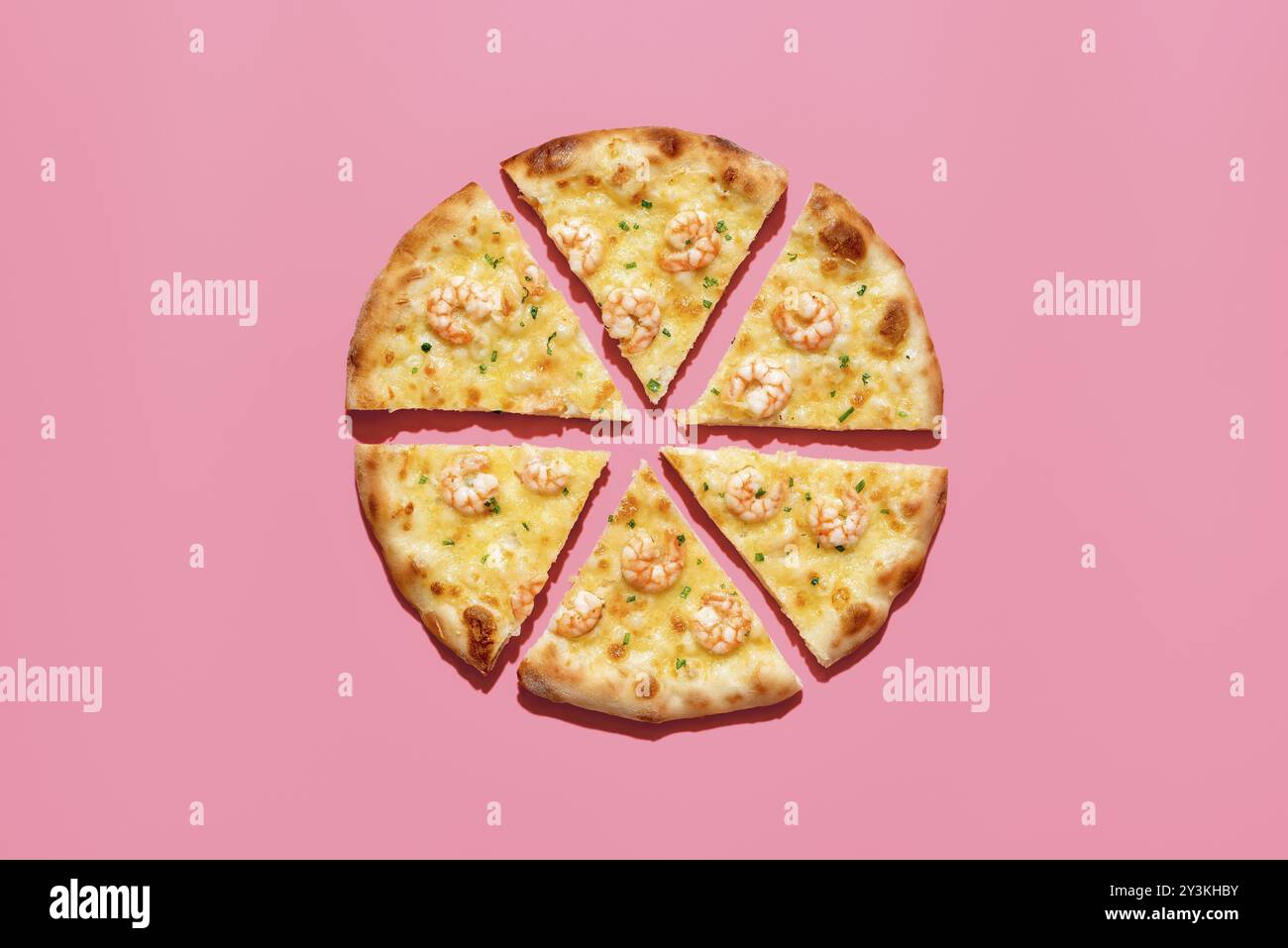 Homemade shrimp pizza in bright light minimalist on a pink table. Top view with a sliced pizza isolated on a vibrant colored background Stock Photo