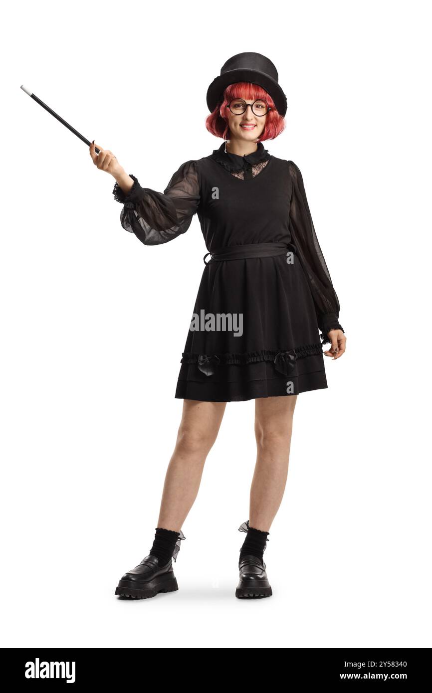 Full length portrait of a female magician with a top hat and black dress holding a magic wand isolated on white background Stock Photo