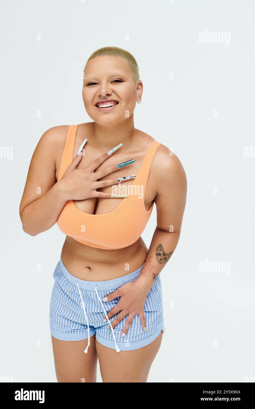 A young bald woman confidently expresses joy while wearing a colorful ensemble. Stock Photo