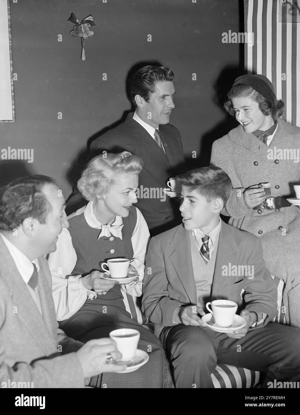 'Master and Miss America' have tea with the star of 'Guys and Dolls' at the Coliseum. Two children, a boy and girl, recently won a television competition in America and the prize was a four-day visit to London to see the sights and also to attend the Schoolboys Own Exhibition. They arrived in London this afternoon and immediately went to the television studios at Lime Grove to rehearse for their appearance in 'Teleclub.' Afterwards, they went to the London Coliseum Theatre where they had tea with the stars of the current musical 'Guys and Dolls,' Miss Vivian Blaine, Edmund Hockridge, and Tony Stock Photo