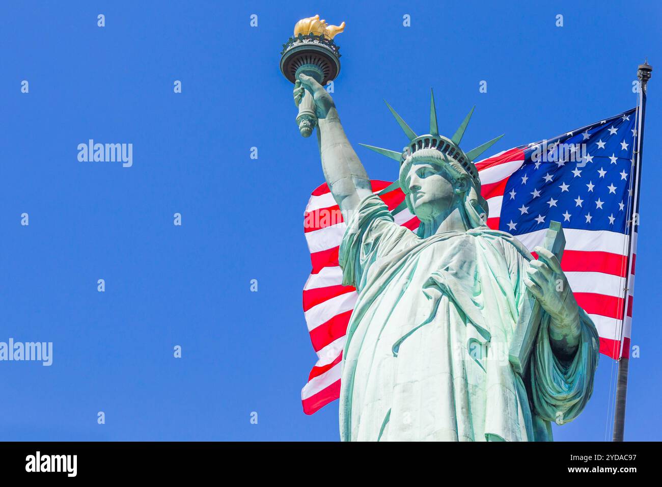 Statue of Liberty with a large american flag and New York skyline in the background Stock Photo