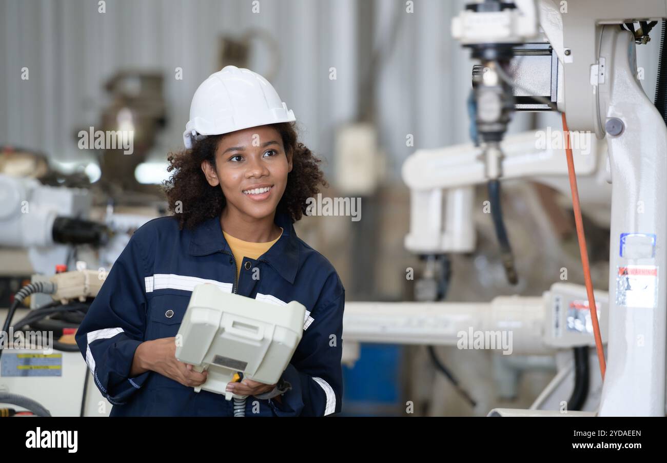 A young female worker is controlling a mechanical robot. Stock Photo