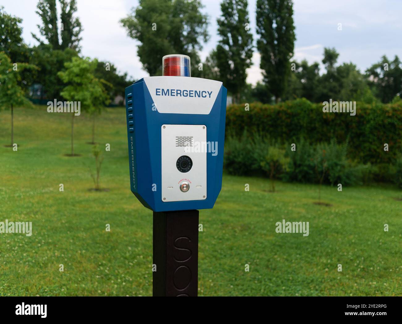 Red emergency police SOS call button with light panel, CCTV camera and speaker for urgent communication with the police in a city park. Civil security Stock Photo