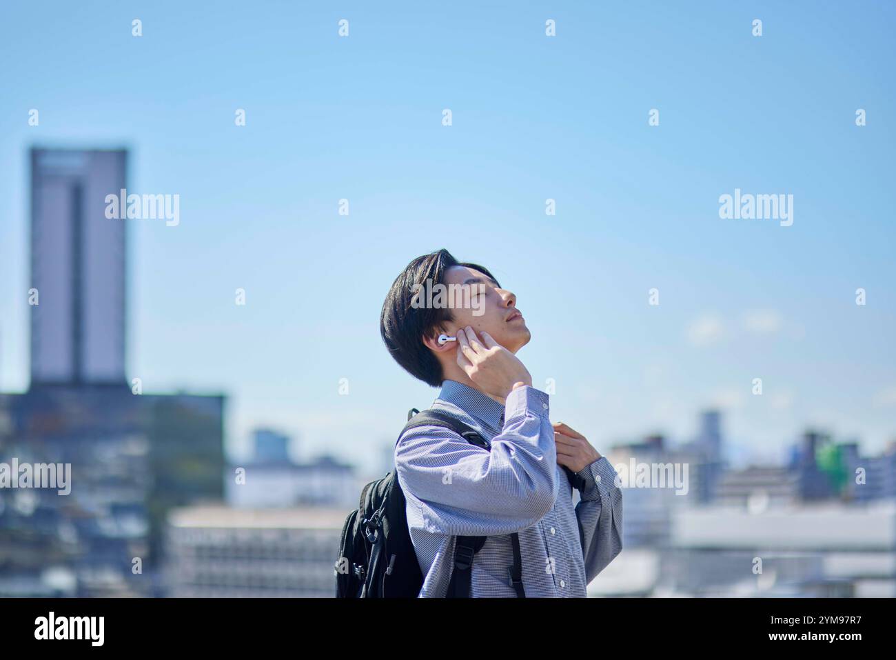 Male Japanese university student on his way to school listening to music with wireless earphones Stock Photo