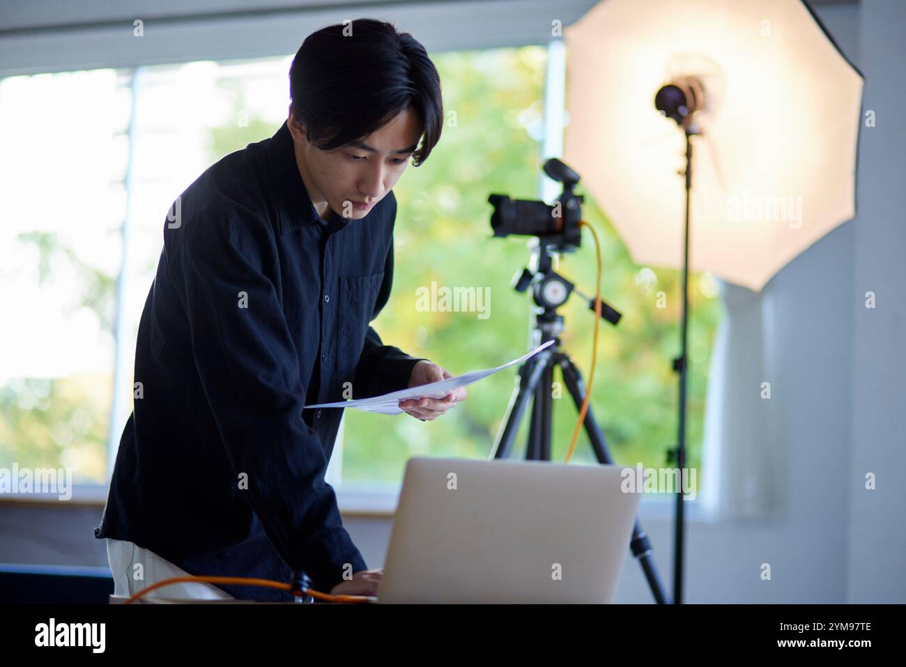 A Japanese male photographer operating a laptop computer in a photo studio Stock Photo