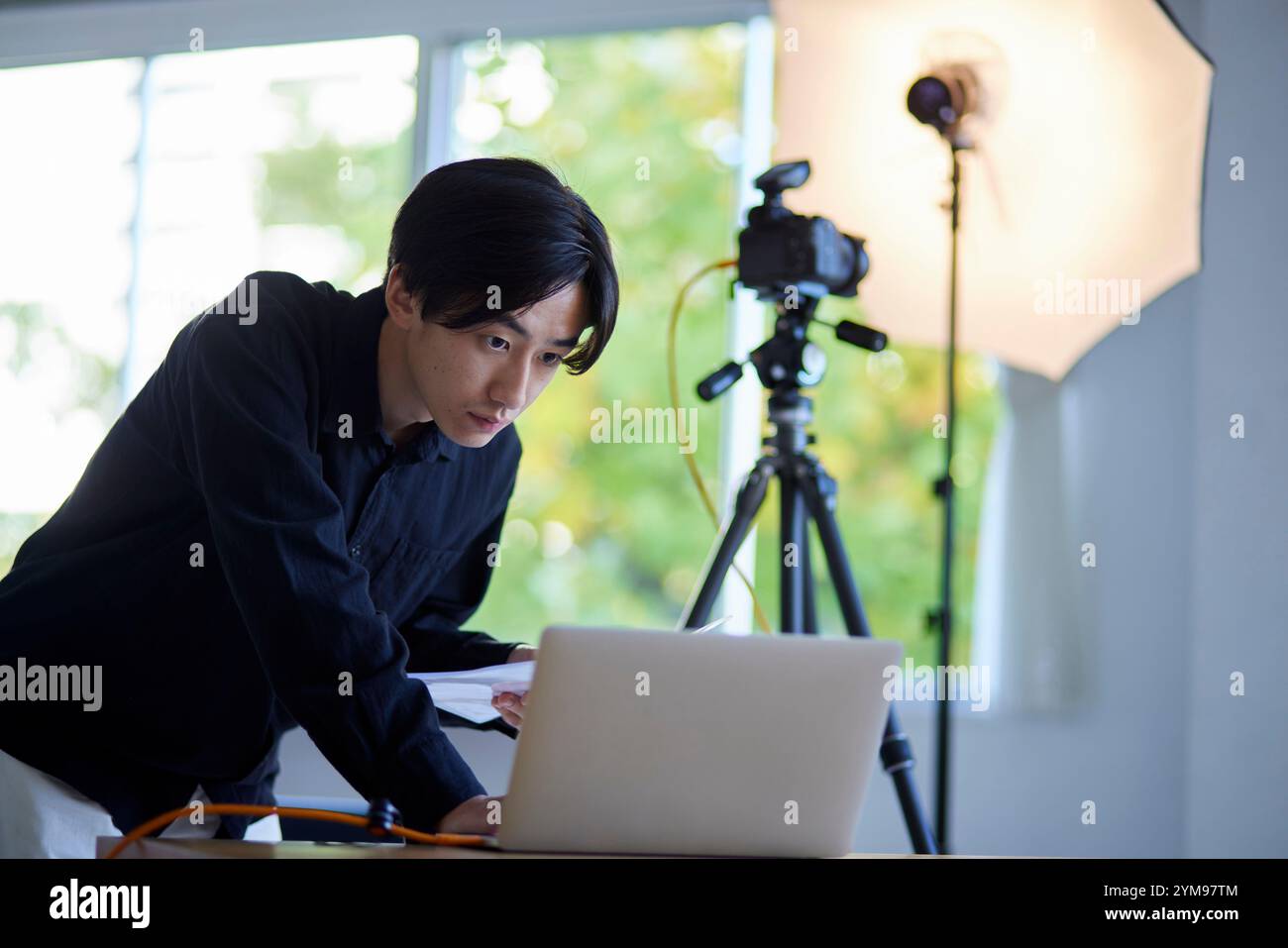 A Japanese male photographer operating a laptop computer in a photo studio Stock Photo