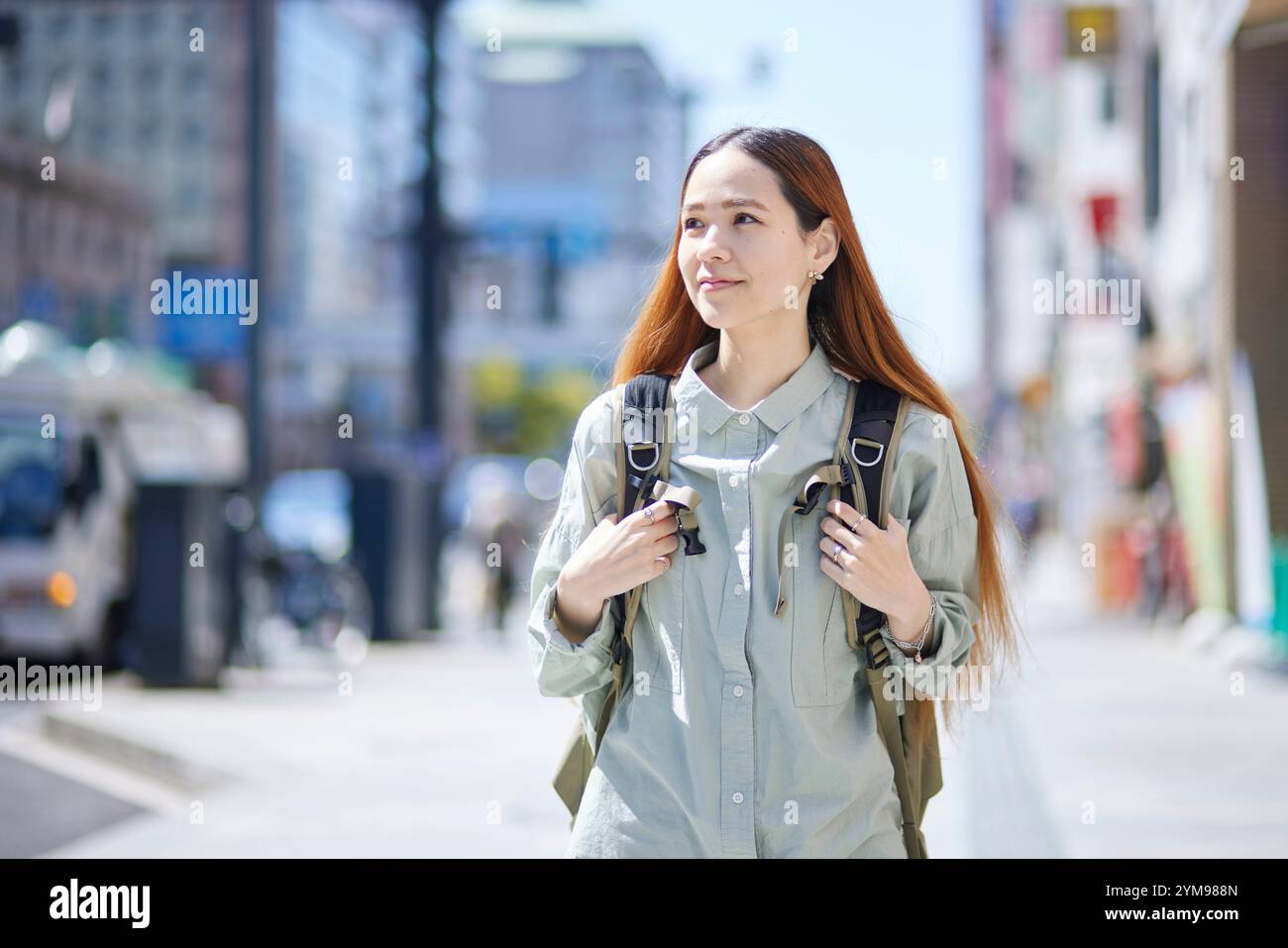 Female international traveller walking through city with backpack on her back Stock Photo