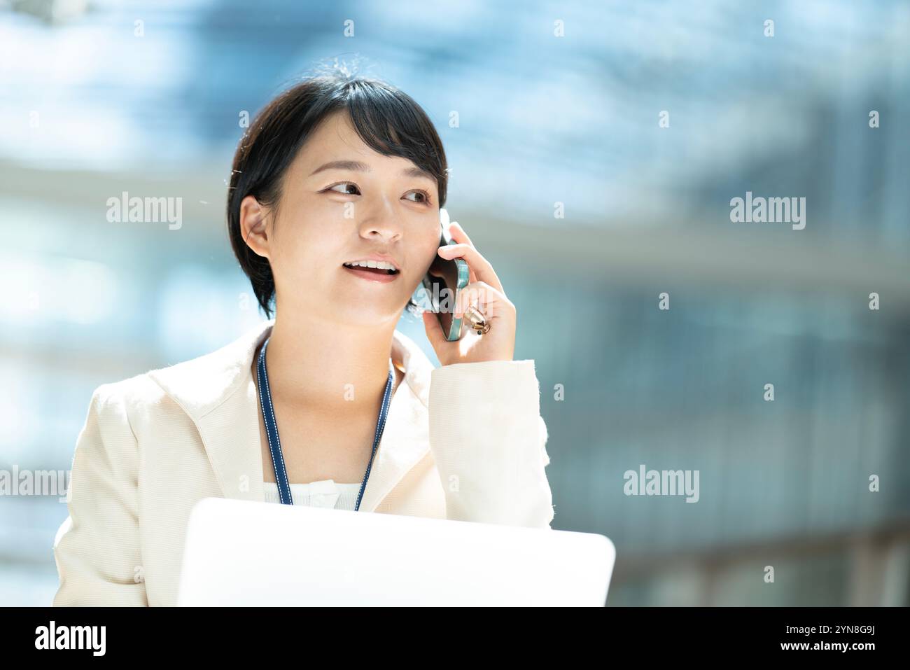 Woman in suit with computer open and talking on phone Stock Photo