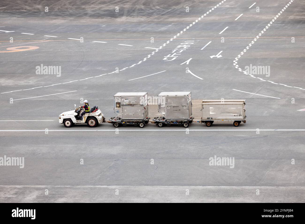 Airport ground vehicle towing cargo containers on the tarmac Stock Photo