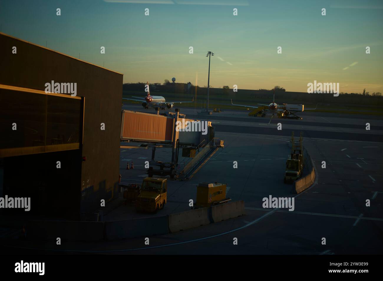 Sunset hues bathe an airport tarmac with airplanes and ground support equipment, Vienna, Austria Stock Photo