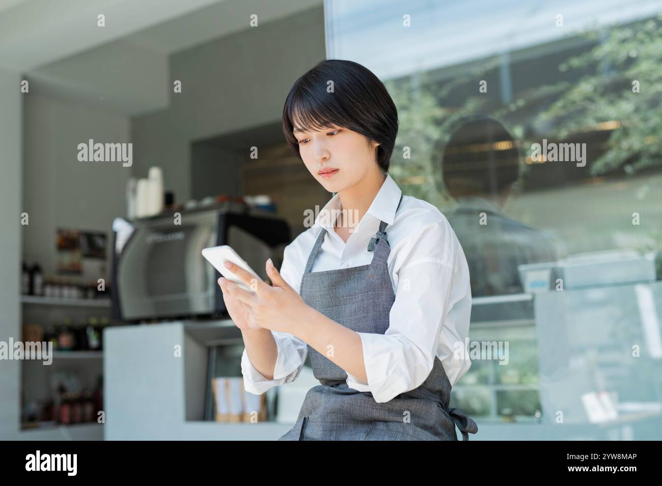 Café Female staff using smartphone Stock Photo