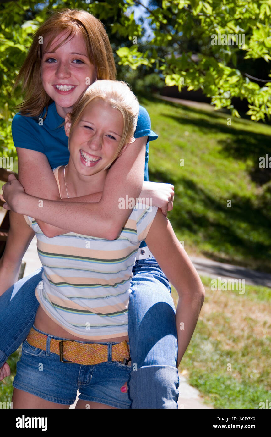 Two young girls, one giving a piggyback ride to the other Stock Photo