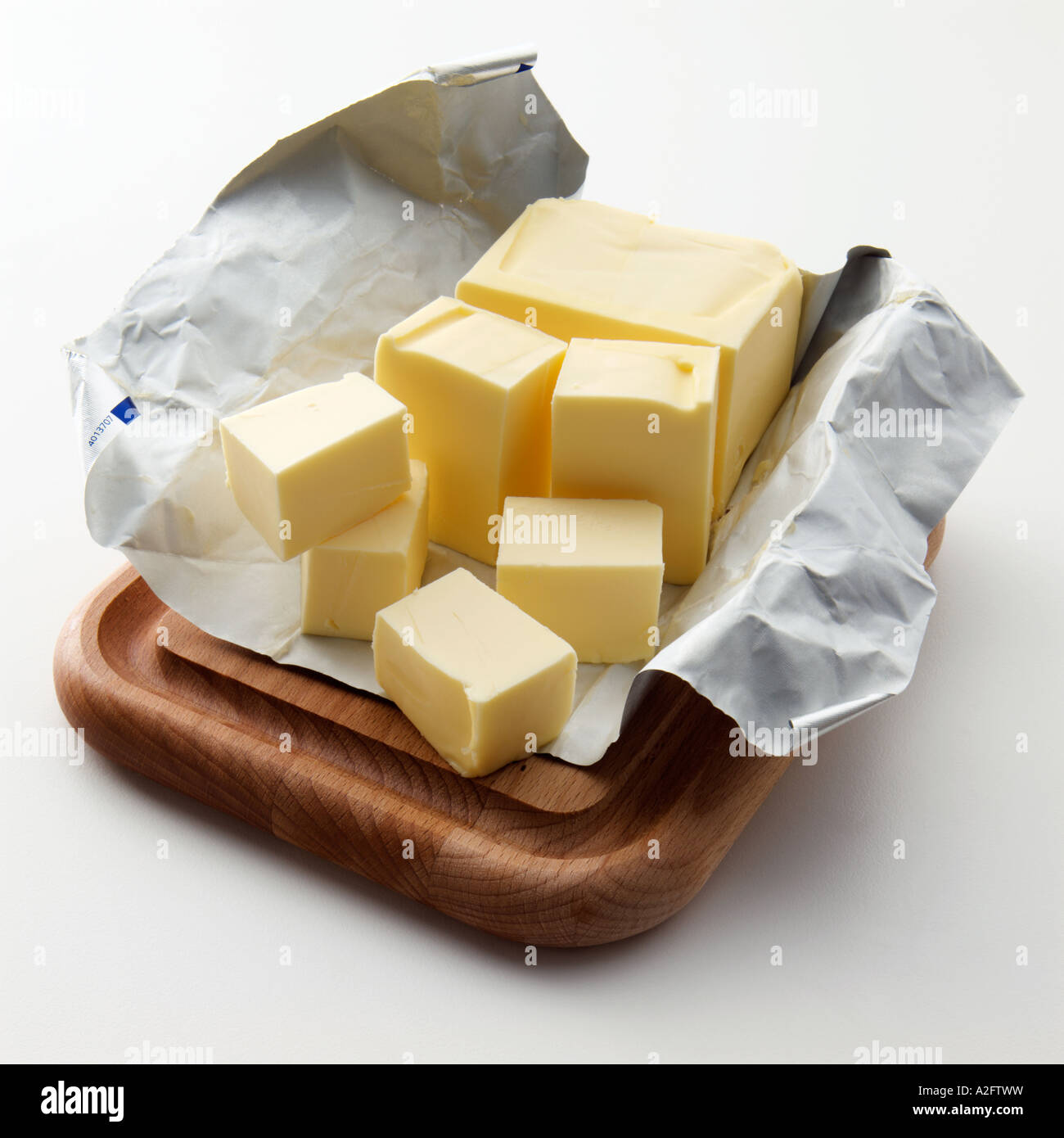 A block of butter partly cut into cubes on silver wrapper Stock Photo