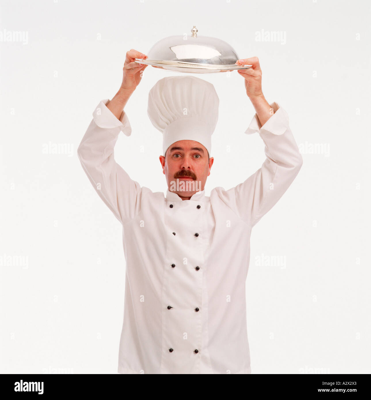 Indoor studio close-up of male professional chef in white tunic wearing chef's hat. Stock Photo