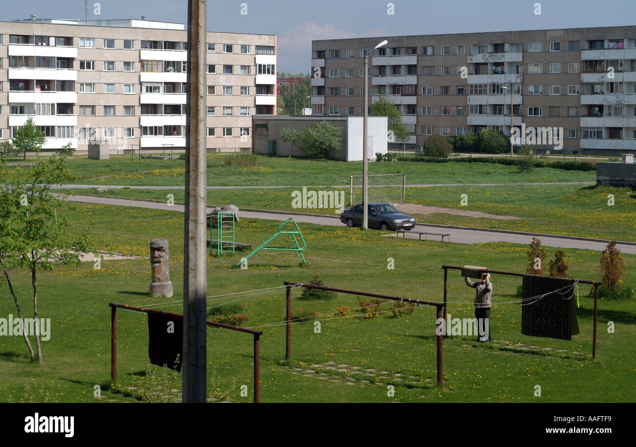 Man hangs out rug to dry in community area of appartment block parnu Stock Photo