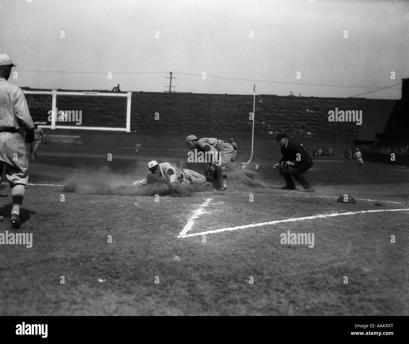 1930s BASEBALL PLAYER SLIDING INTO HOME BASE CATCHER UMPIRE Stock Photo