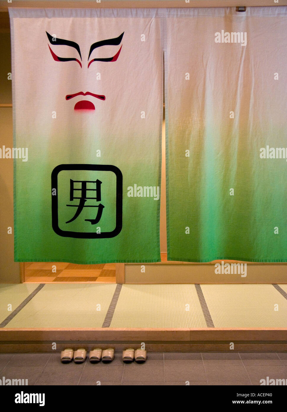 Kabuki face on curtain hanging at entry to men s public bath with slippers Stock Photo