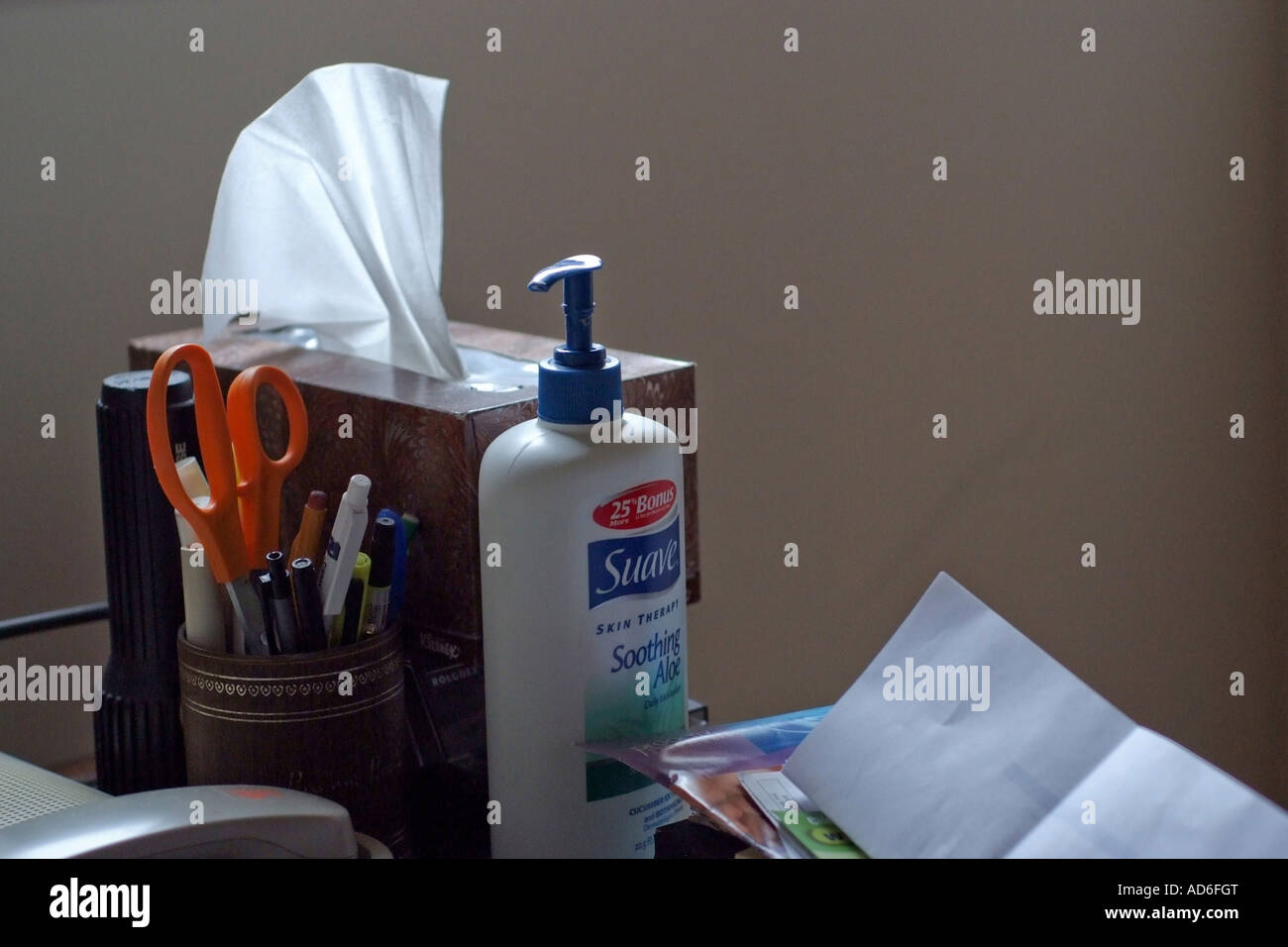 Tissue paper box, hand lotion, flash light, phone and stationary on table top. Stock Photo