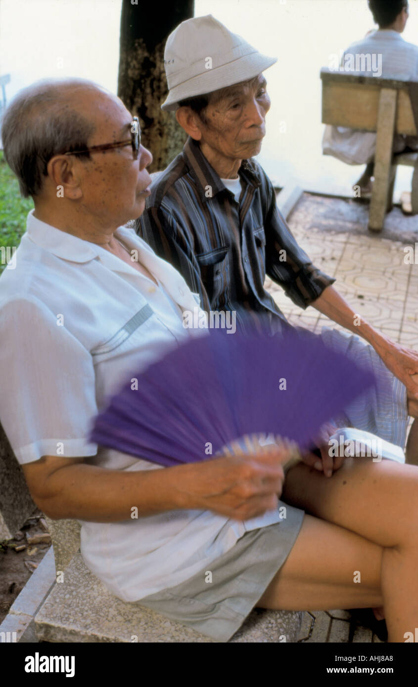 Men sitting by Hoan Kiem Lake Vietnam Stock Photo